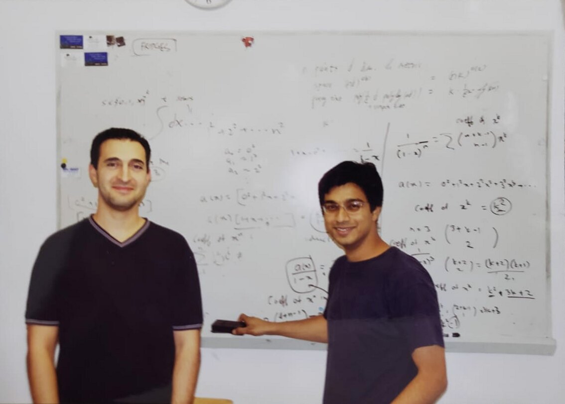 Two collaborators standing in front of a whiteboard covered with equations