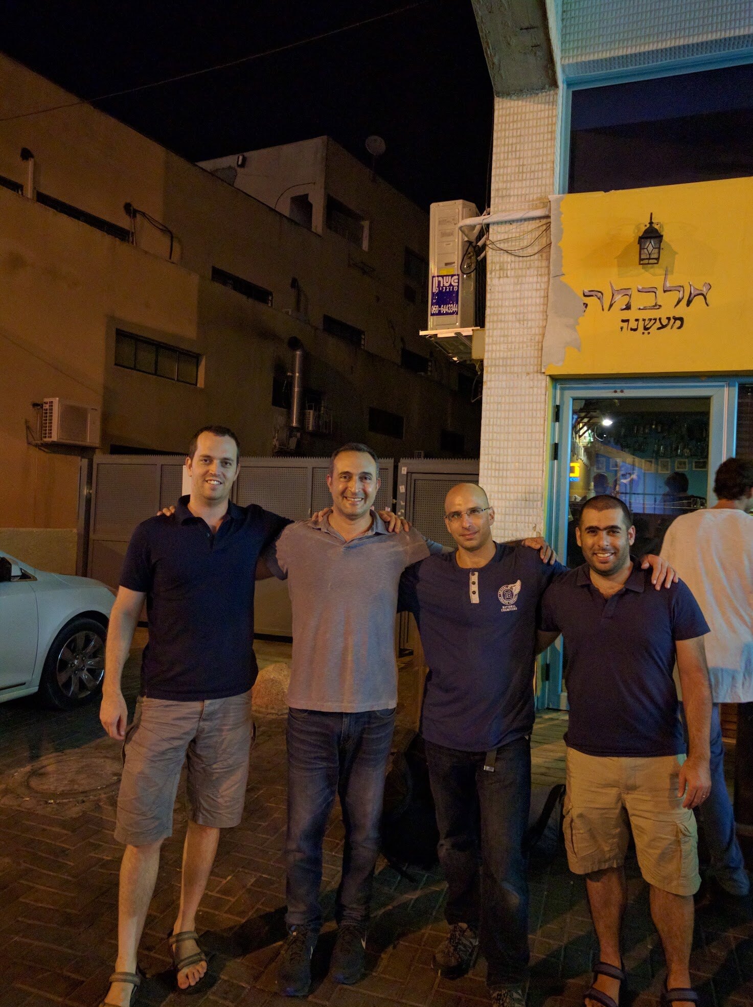 Four friends standing together outside at night