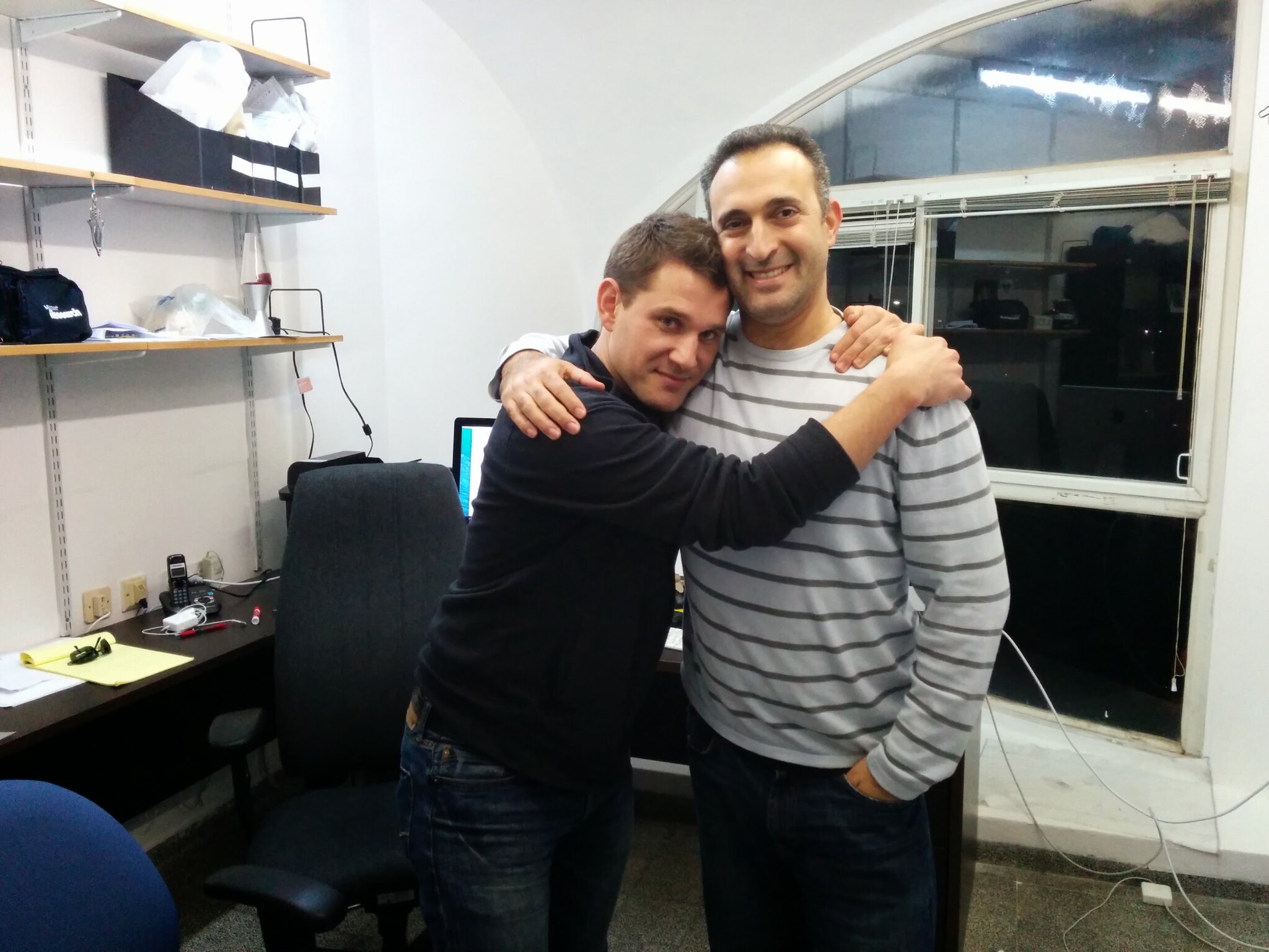 Two collaborators embracing in an office